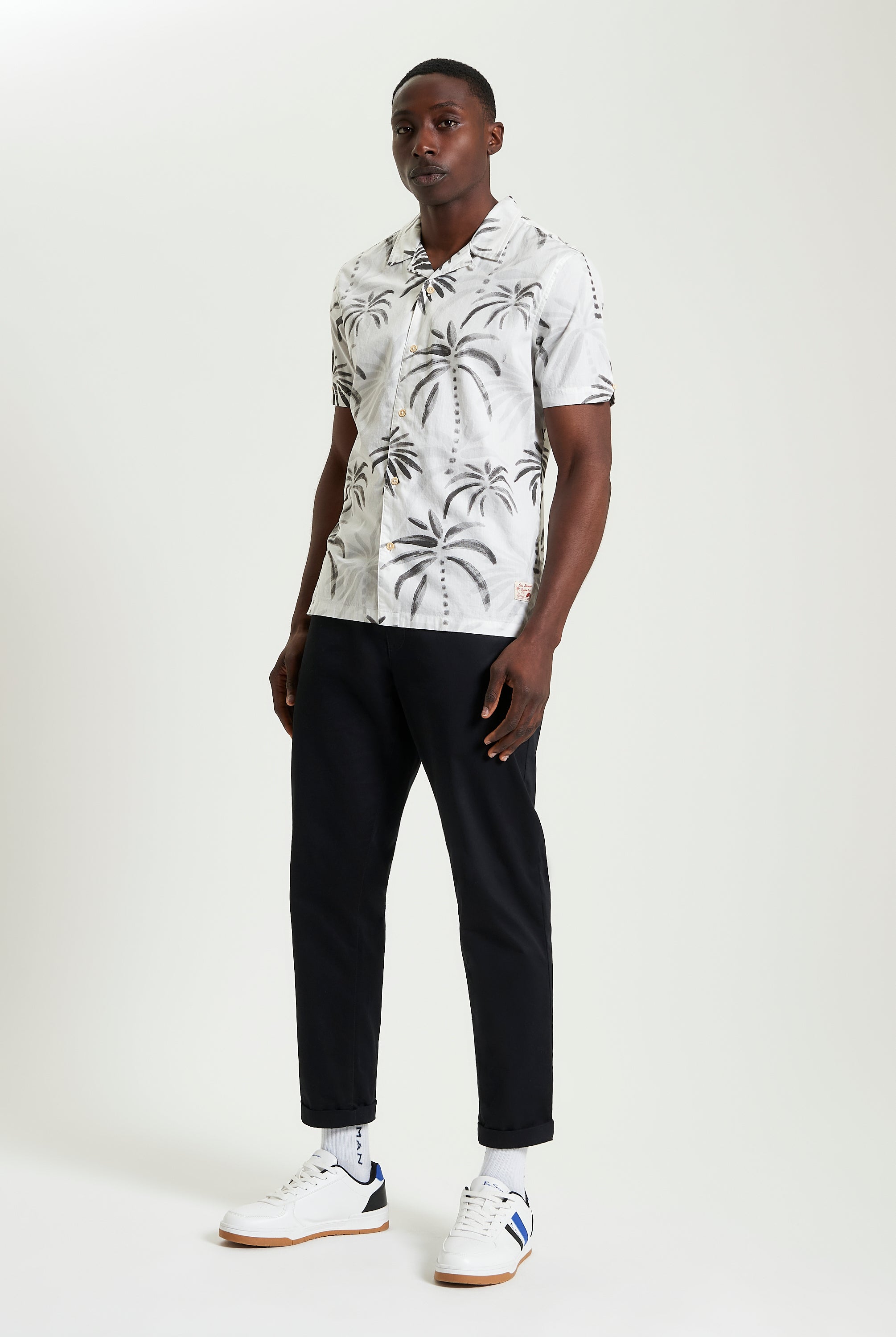 Palm Print Shirt featuring a relaxed collar, short sleeves, and styled with black pants and sneakers.