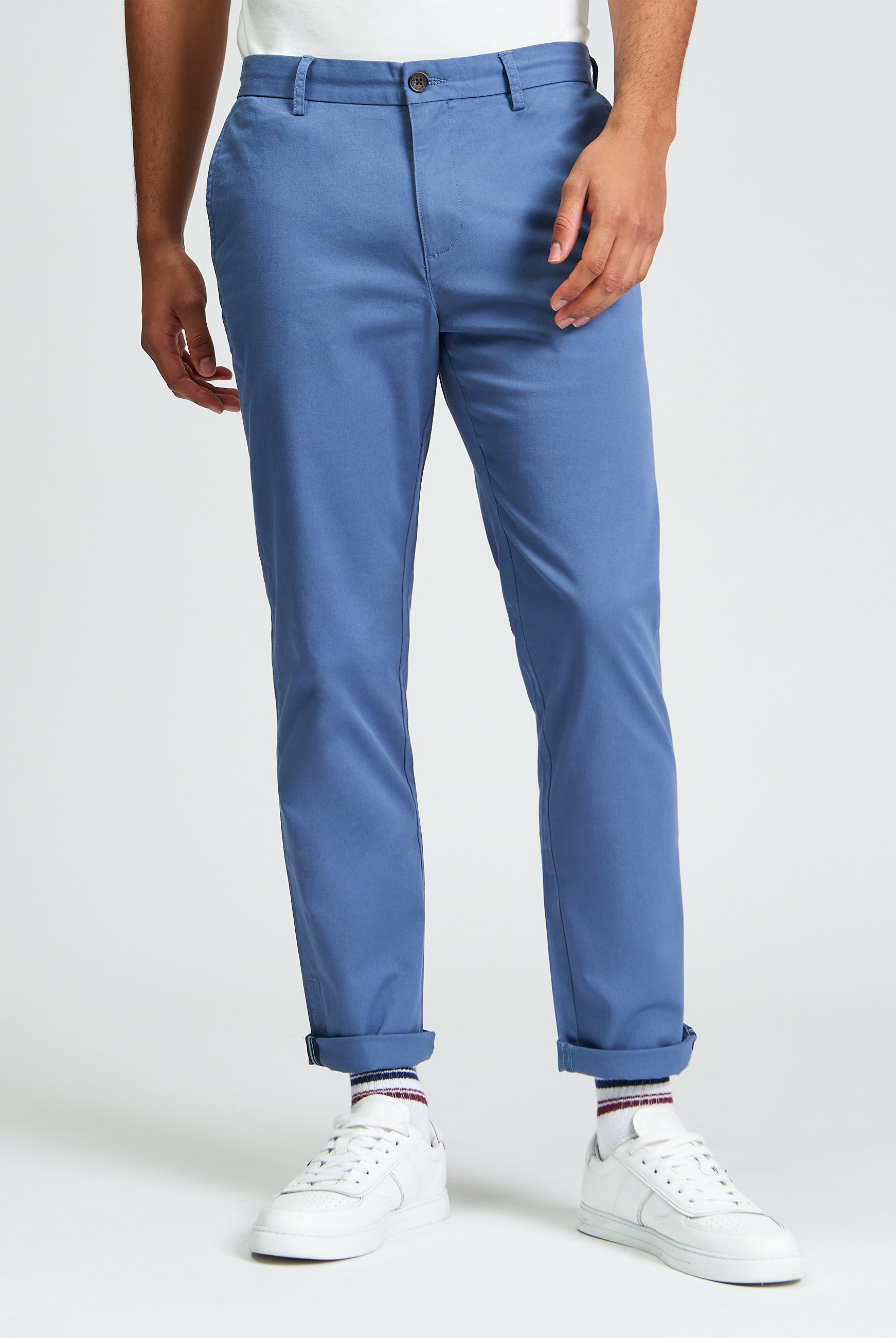 Signature Slim Stretch Chino β blue pants worn with white sneakers and rolled cuffs.