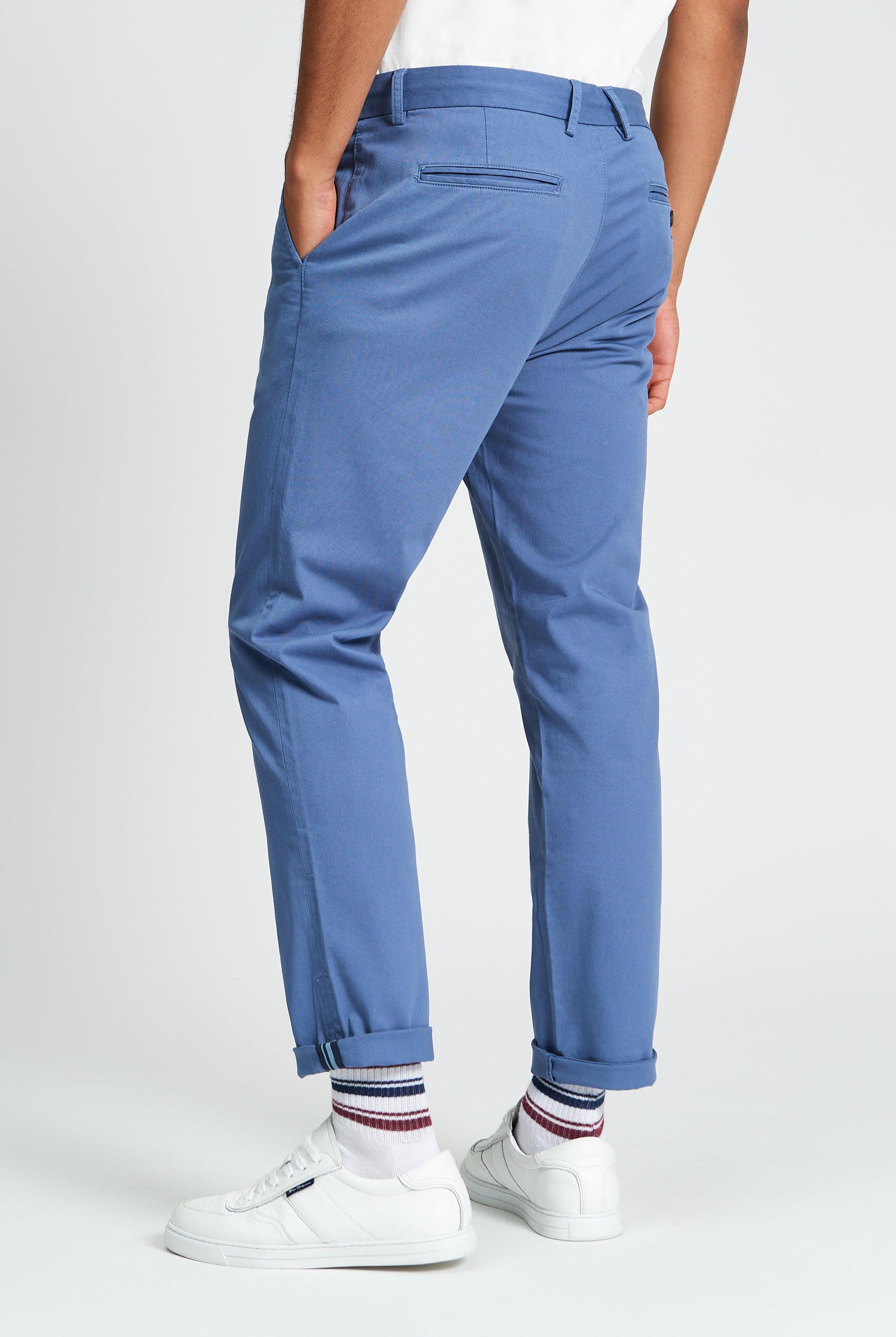 Signature Slim Stretch Chino β blue pants showing back view with rolled cuffs and casual white sneakers.
