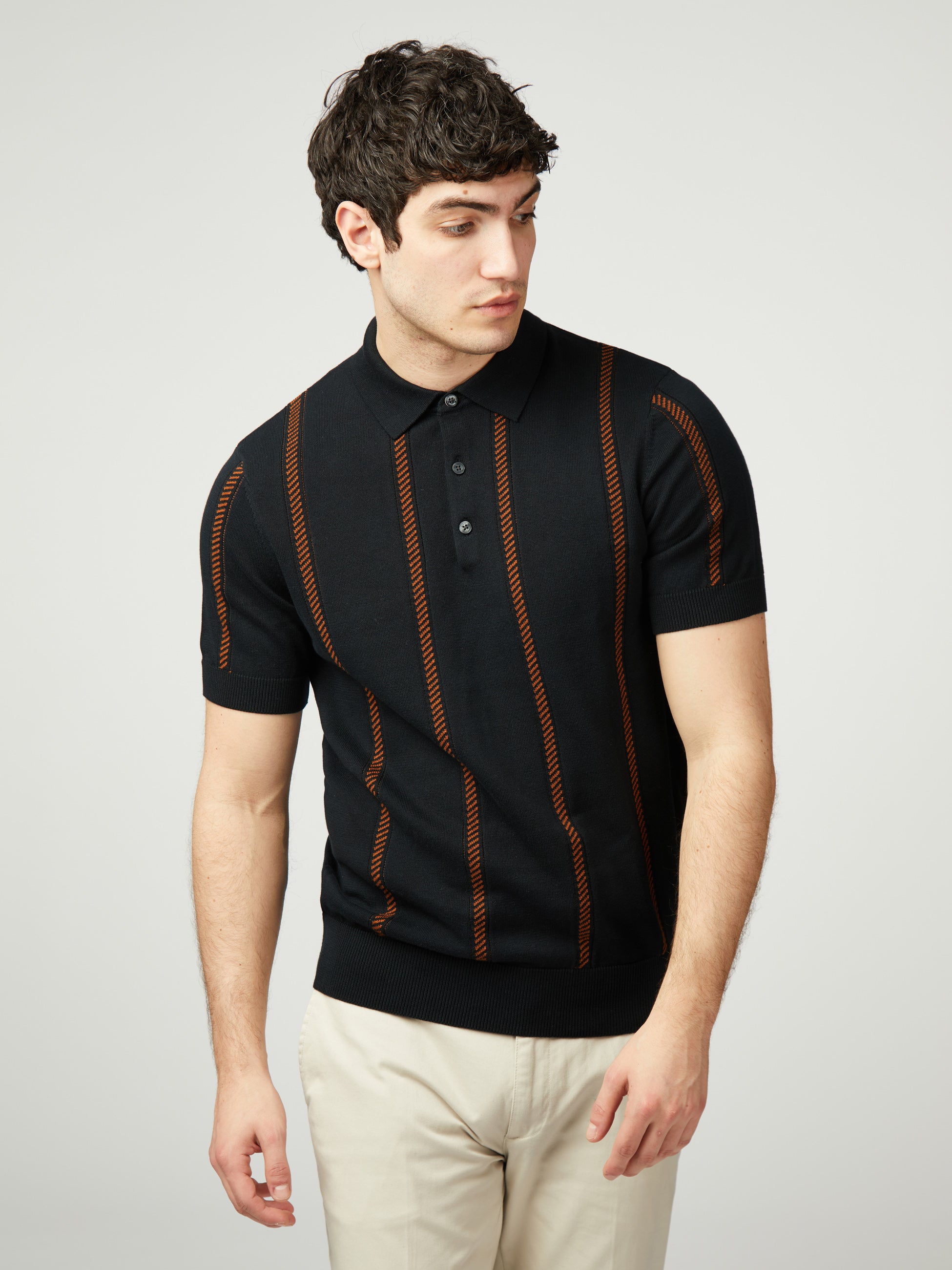 Jacquard Stripe Knitted Polo featuring black and orange stripes on a model, made from 100% organic cotton.