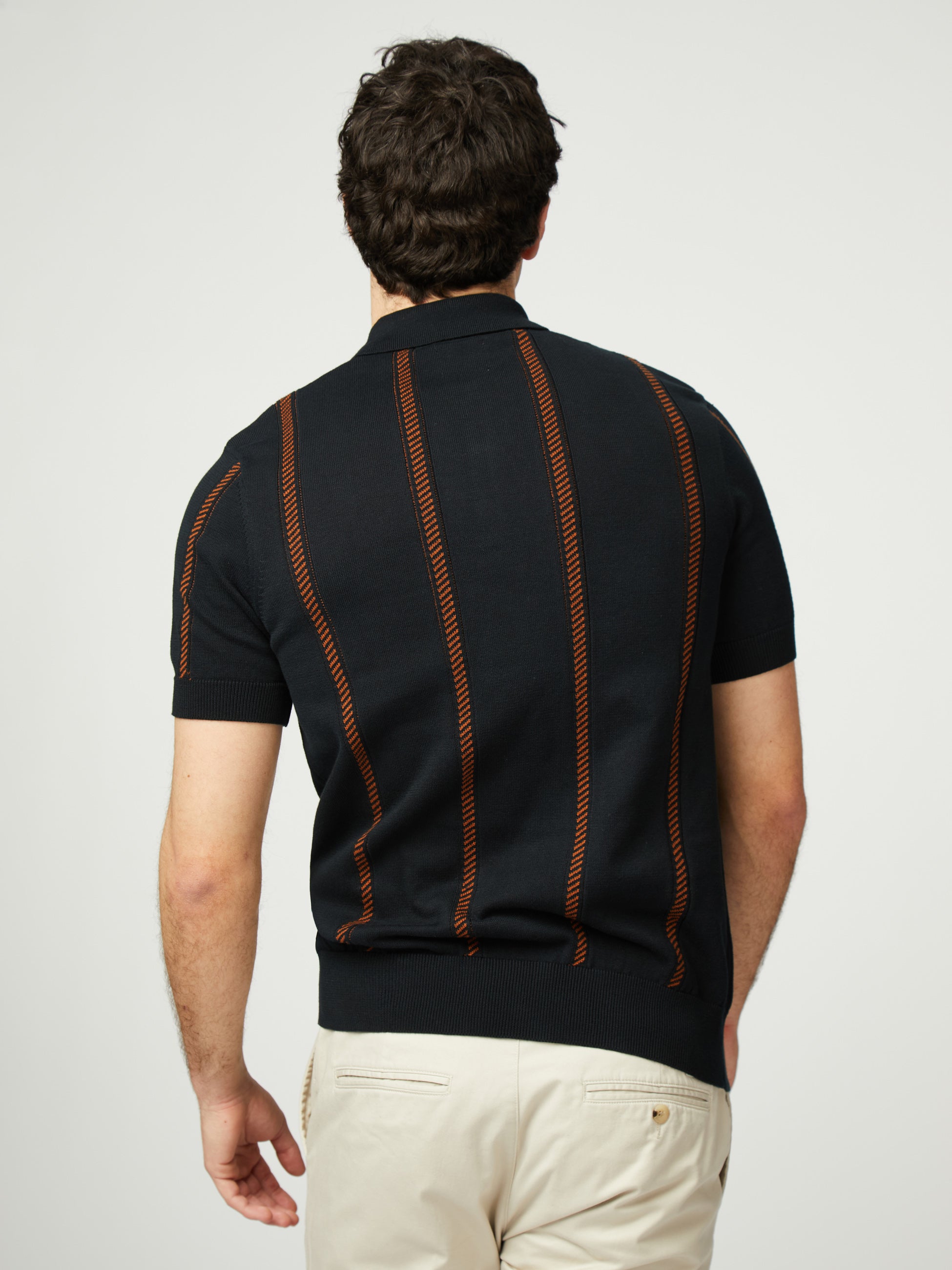 Back view of a man wearing a Jacquard Stripe Knitted Polo with contrasting stripes.
