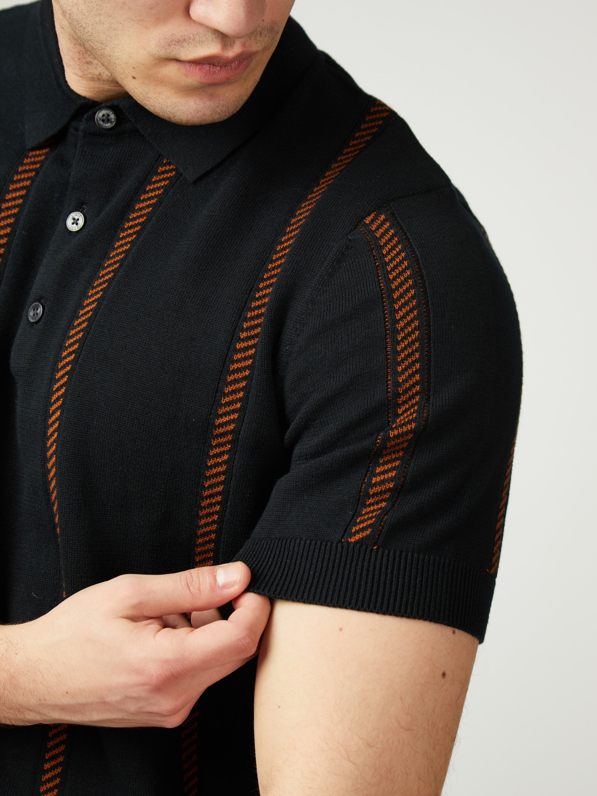 Jacquard Stripe Knitted Polo – Stylish black polo with orange stripes and side seam woven label.