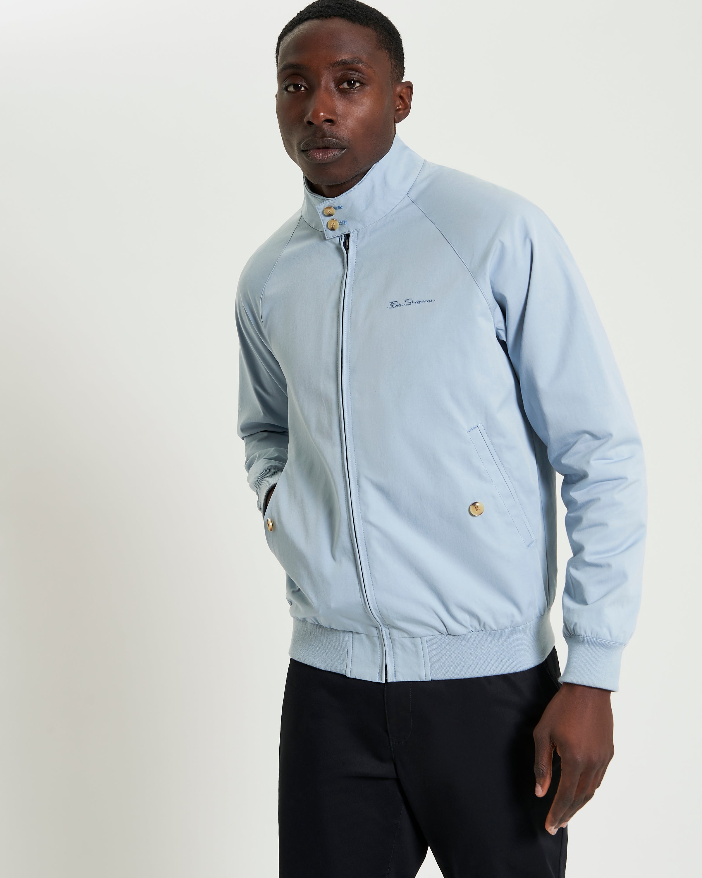 Signature Harrington Jacket in light blue worn by model, featuring a two-button stand collar and front zip closure.