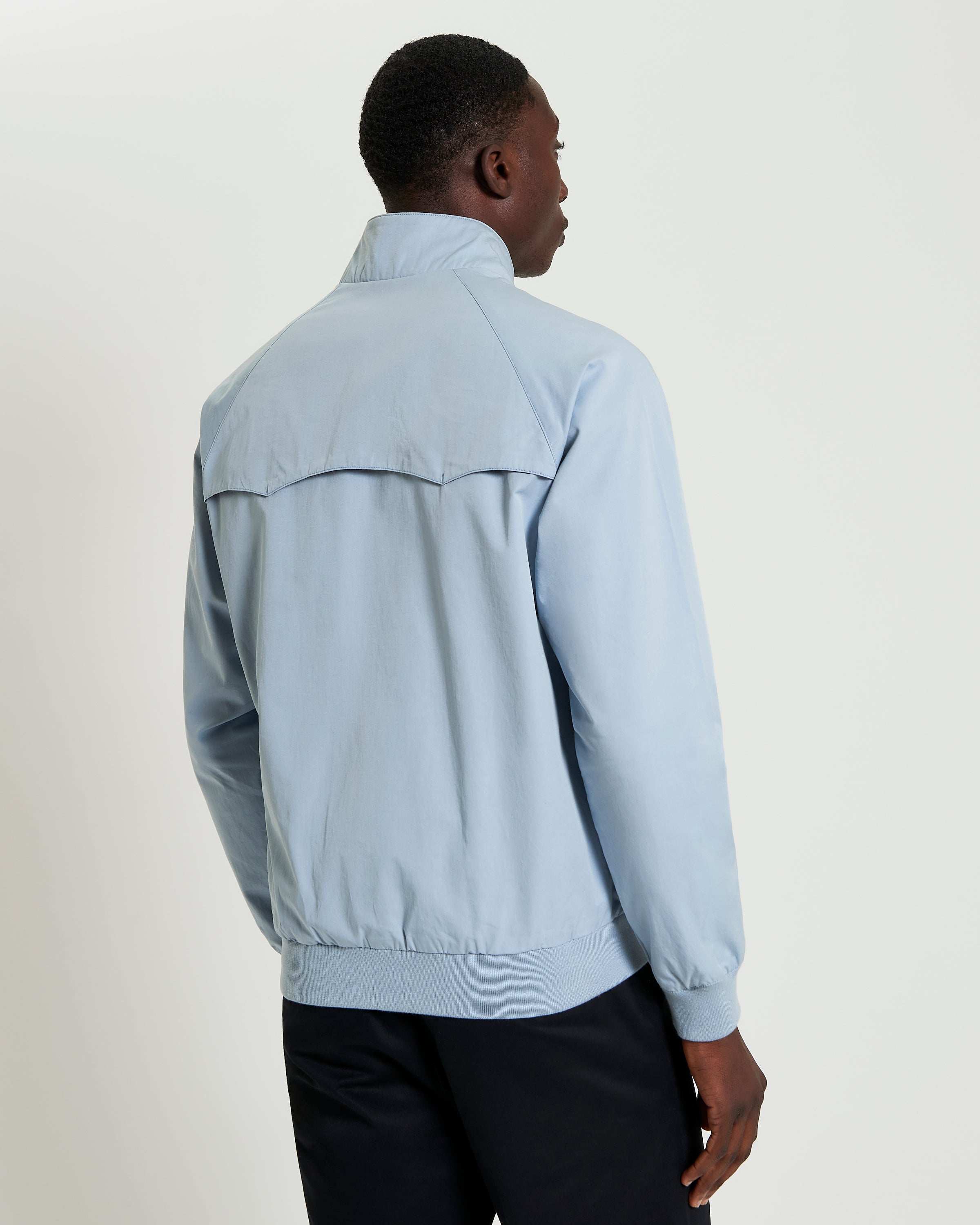 Man showcasing the back view of the Signature Harrington Jacket in light blue.
