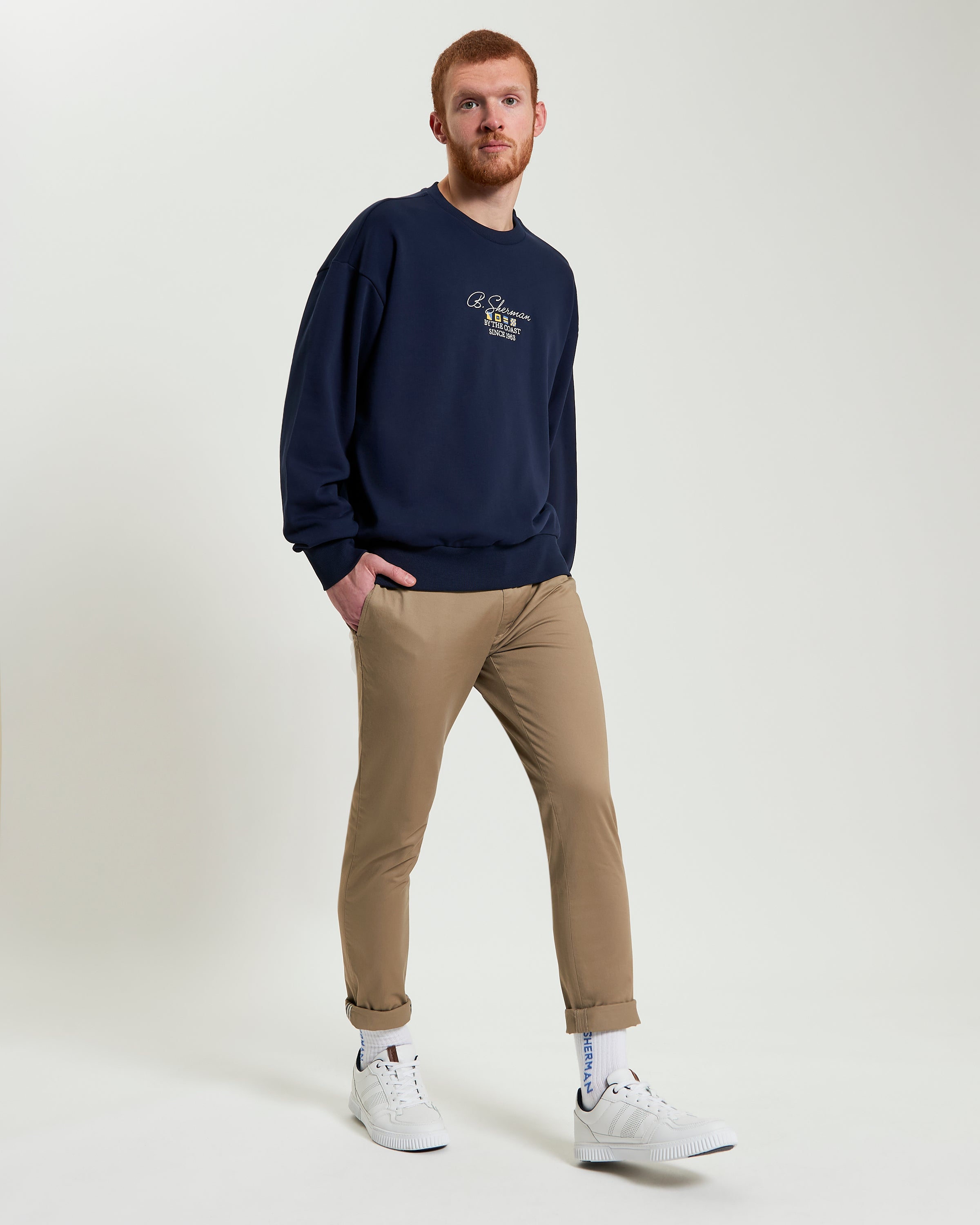 By The Coast Crew sweatshirt modeled by man in navy, featuring relaxed fit and signature Ben Sherman embroidery.