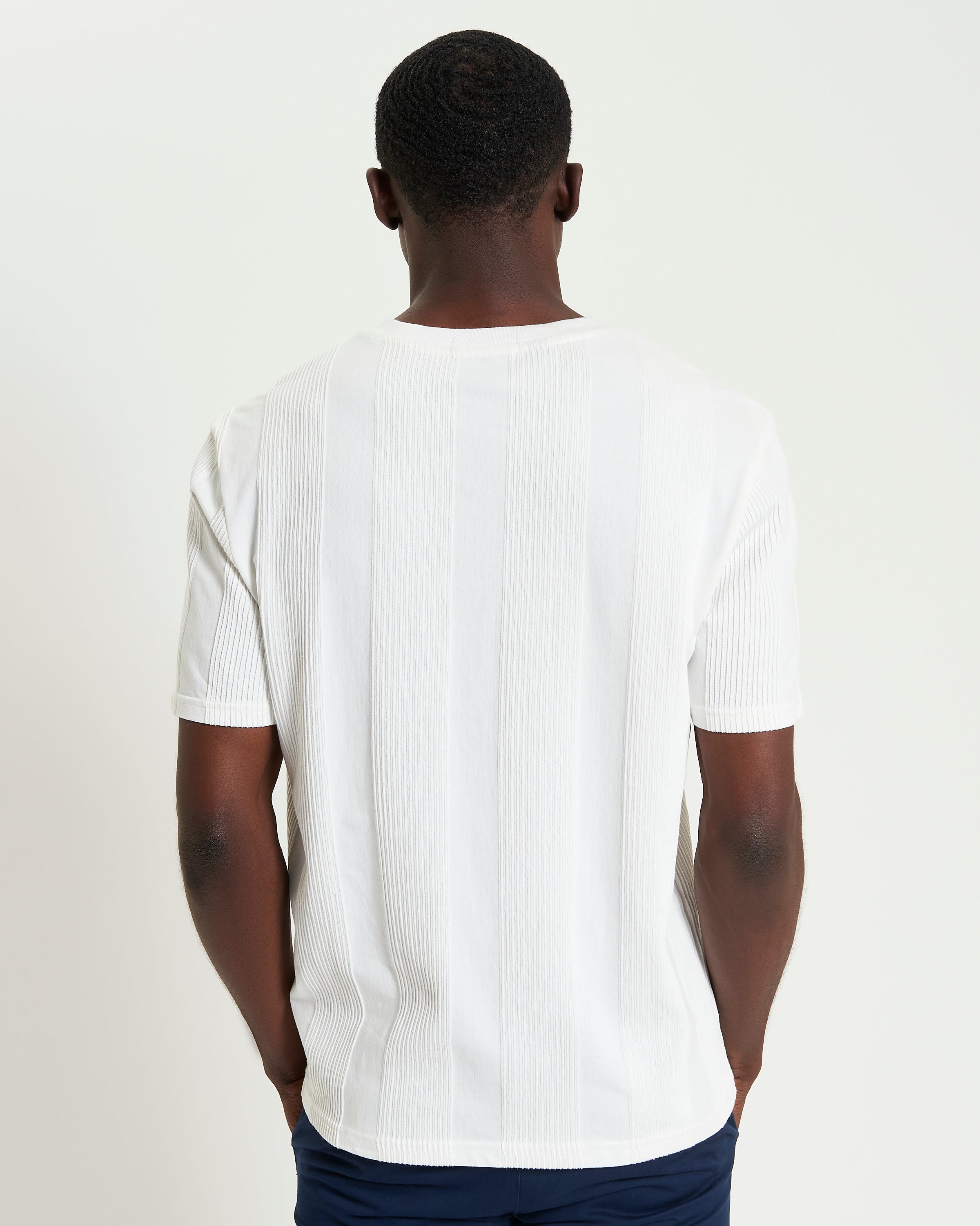 Textured Vertical Stripe Tee – Back view of a model wearing a white textured vertical stripe t-shirt.