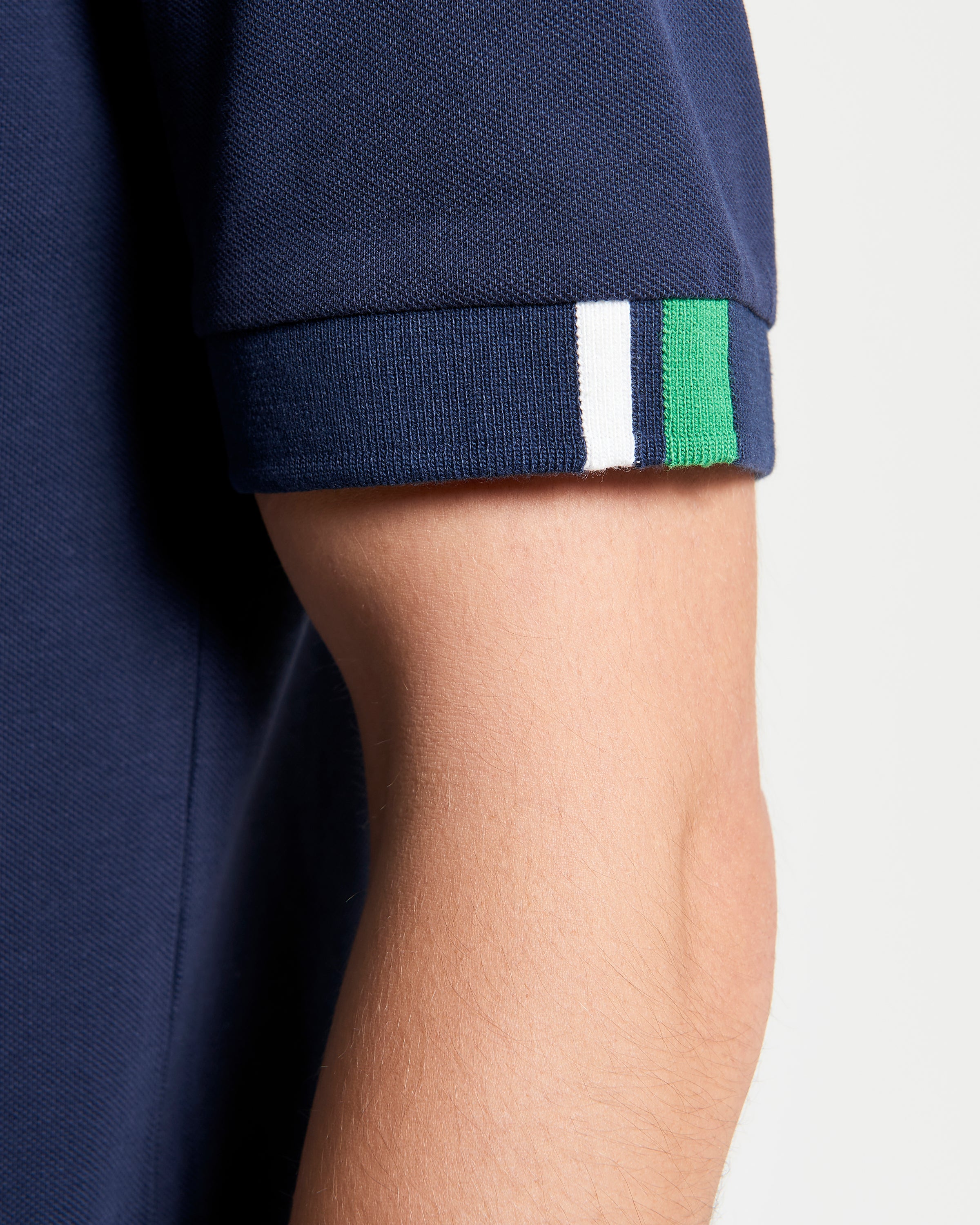 Tipped Pique Tee – close-up of navy shirt sleeve with green, white, and navy accents.