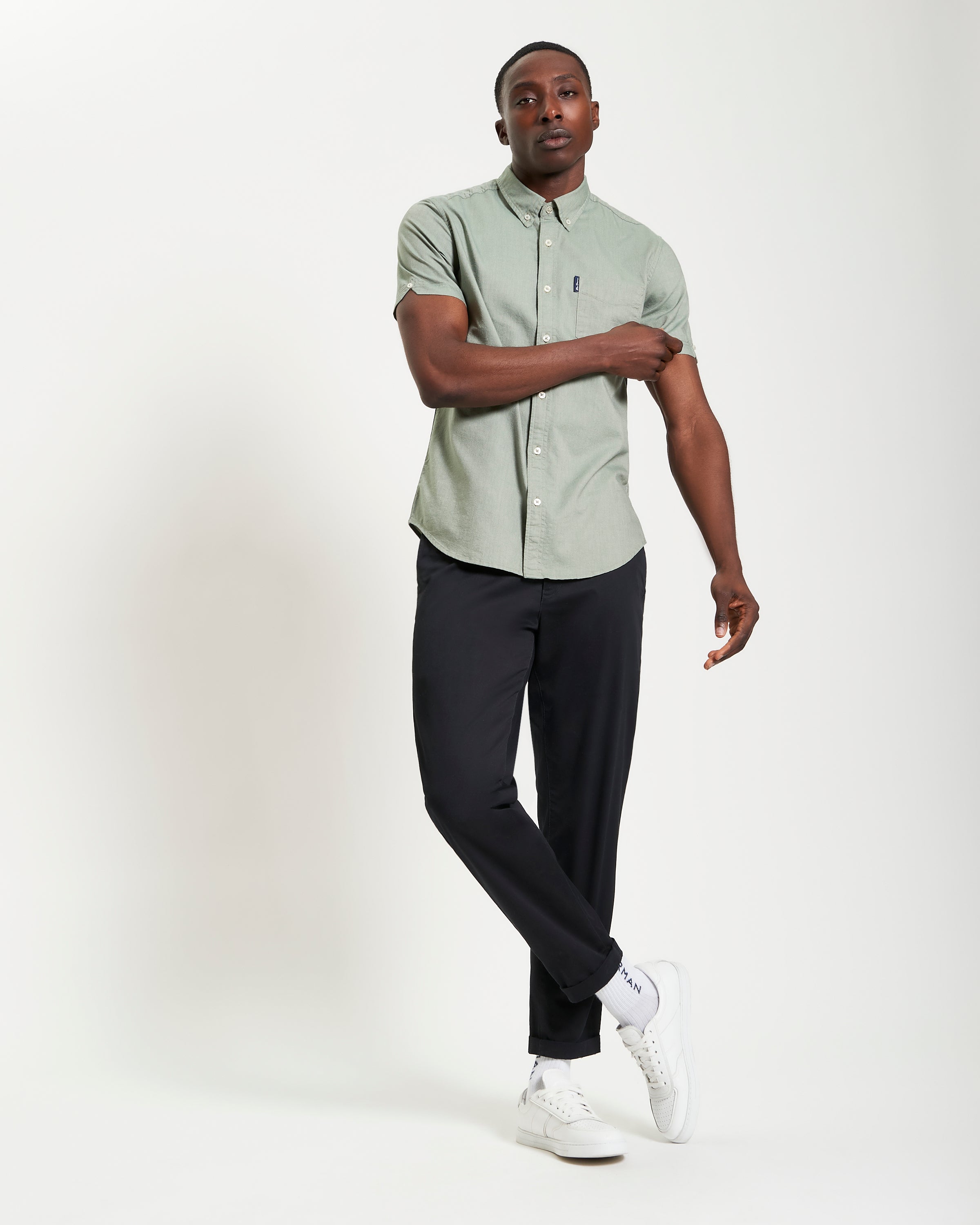 Model wearing Signature Oxford Short Sleeve Shirt in light green; paired with black pants and white sneakers.