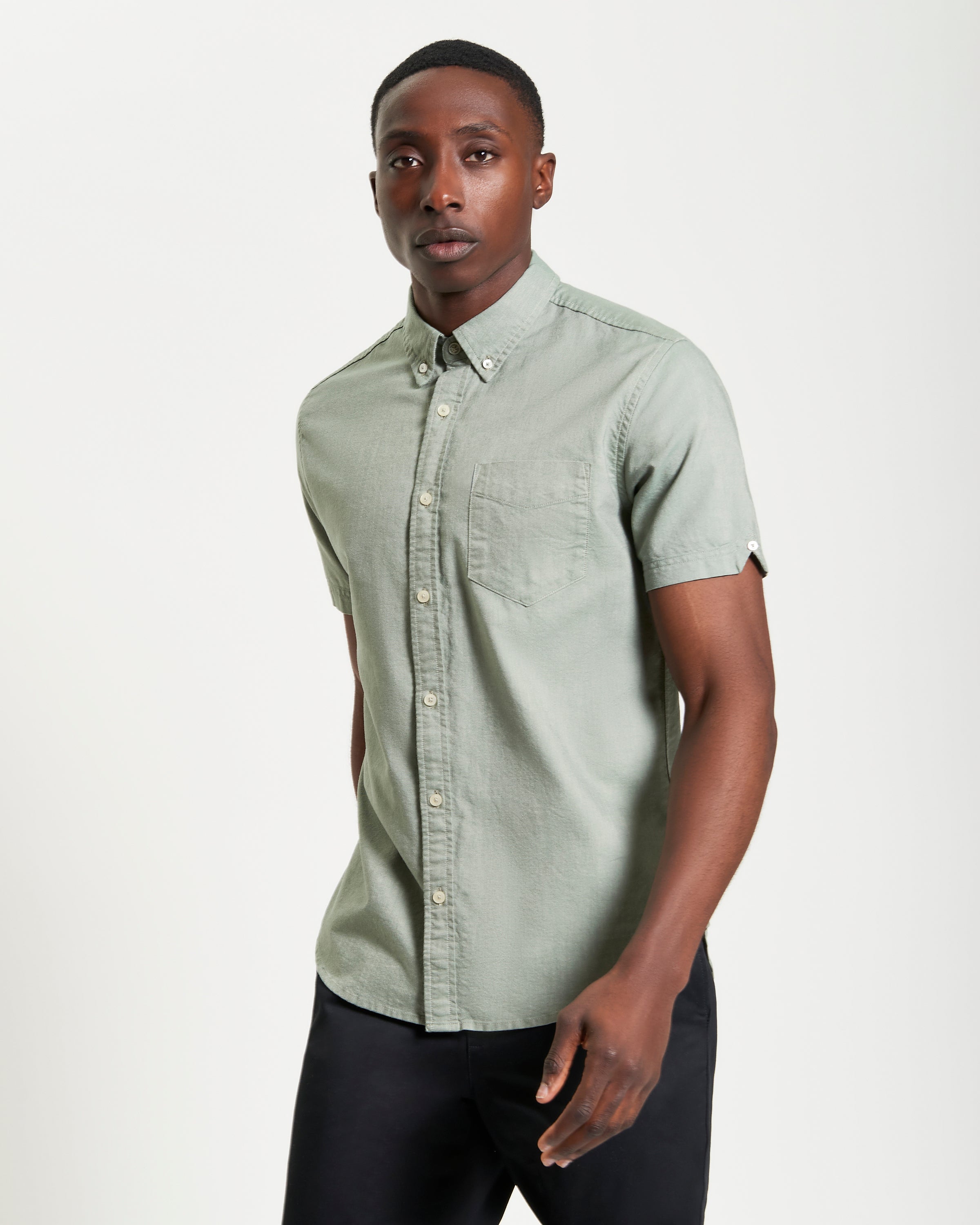 Model wearing the Signature Oxford Short Sleeve Shirt in green, featuring a button-down collar and chest pocket.