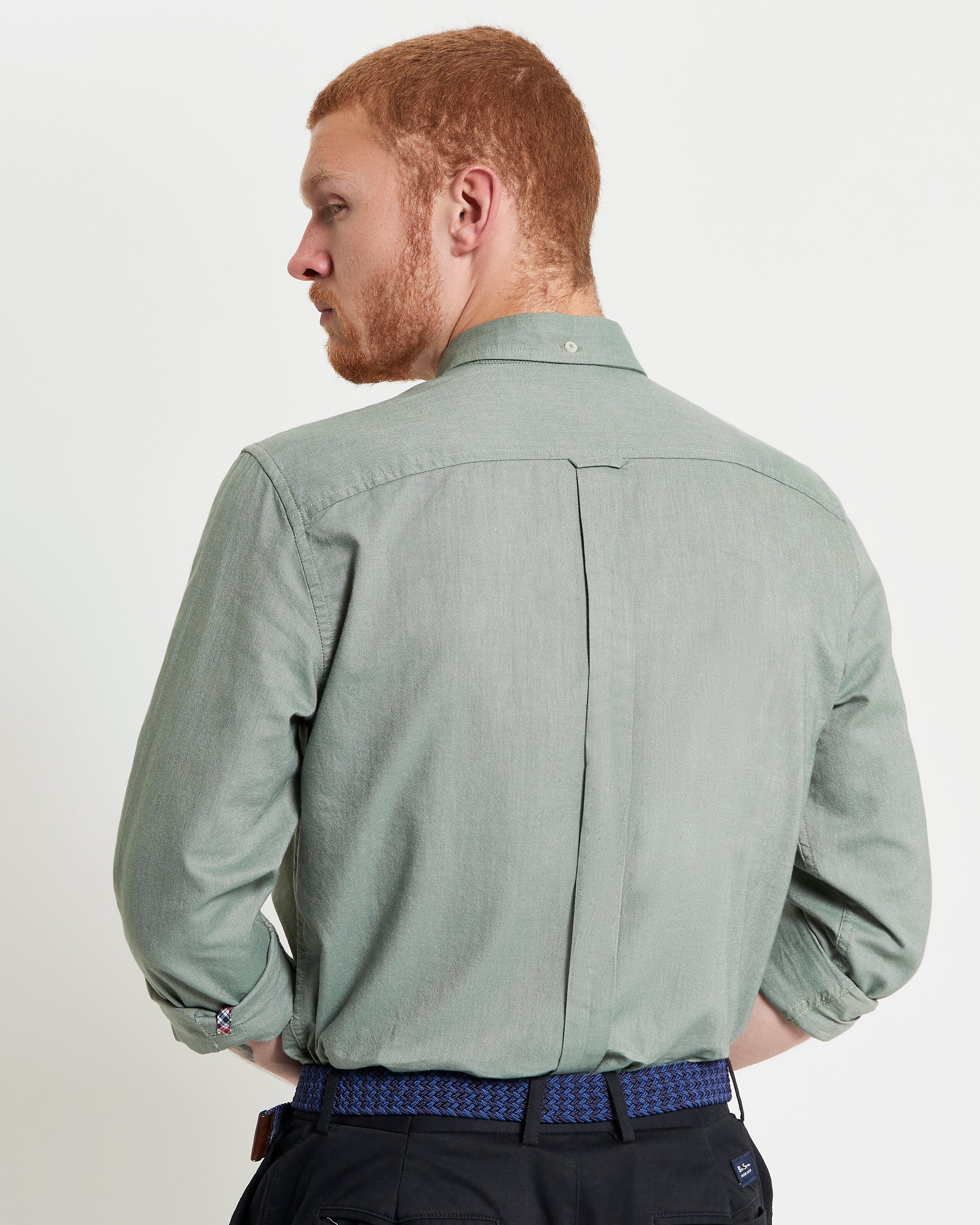 Back view of a man wearing a Signature Oxford Long Sleeve Shirt in green, showcasing the two-finger collar and back box pleat.