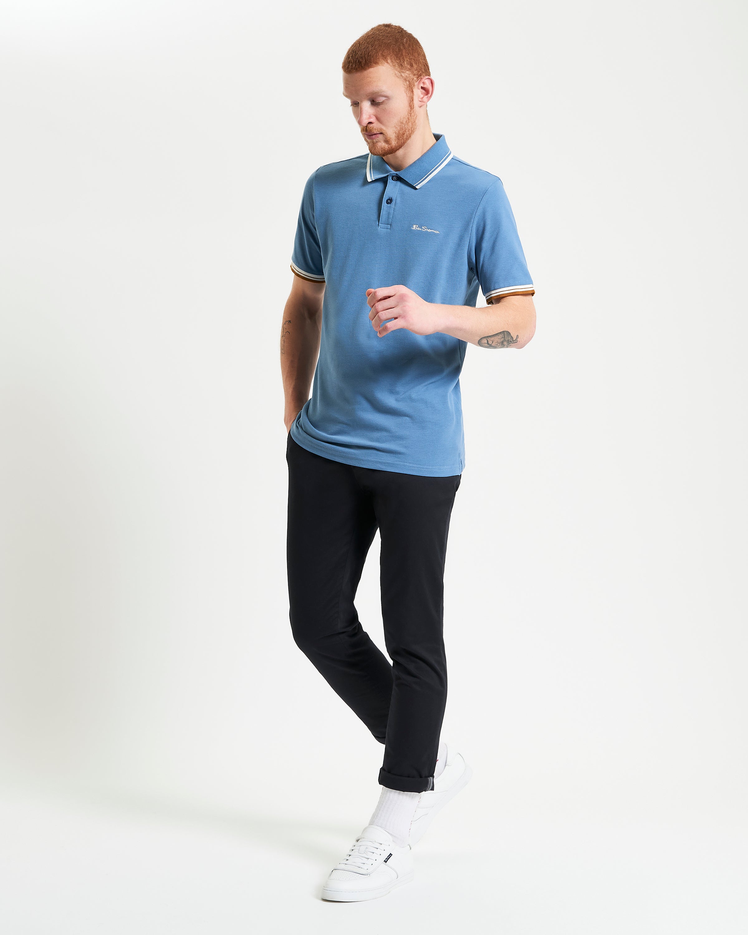 Signature Pique Polo – blue shirt with contrasting details worn with black trousers and sneakers.