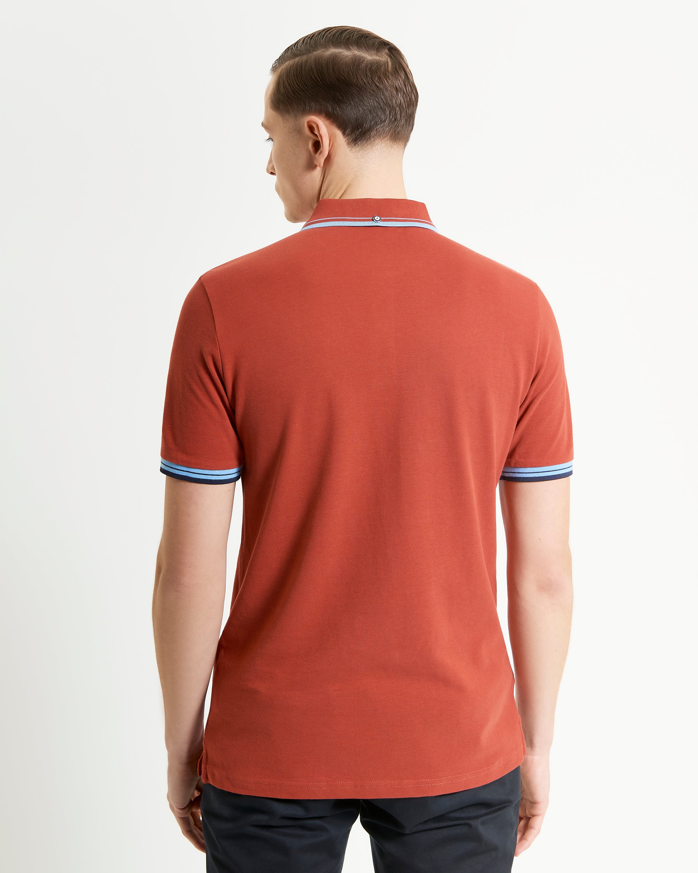 Signature Pique Polo – Back view of model wearing a rust-colored polo shirt with contrast detailing.
