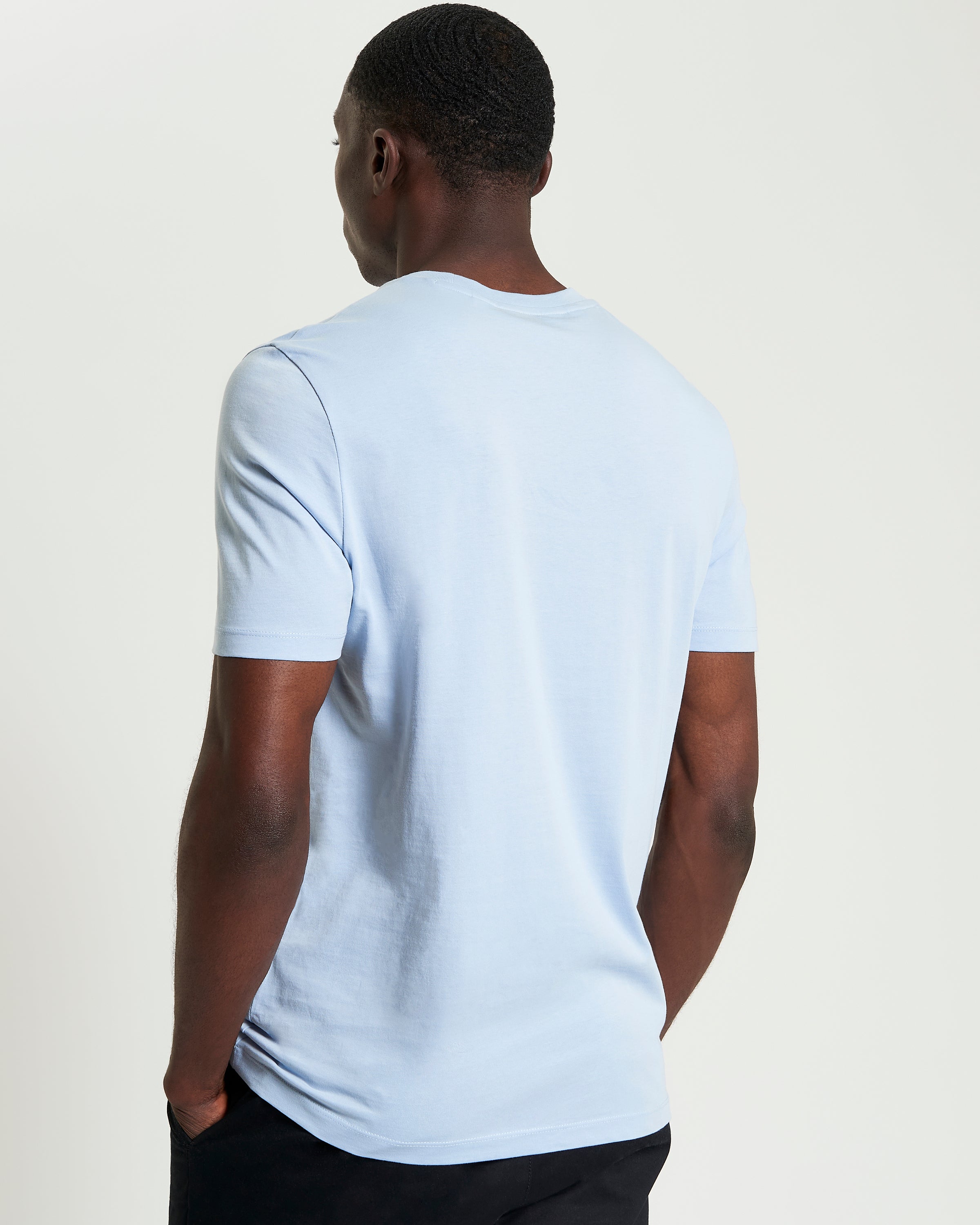 Back view of a man wearing the Signature Tee in light blue, showcasing its comfortable, regular fit and crew neck.