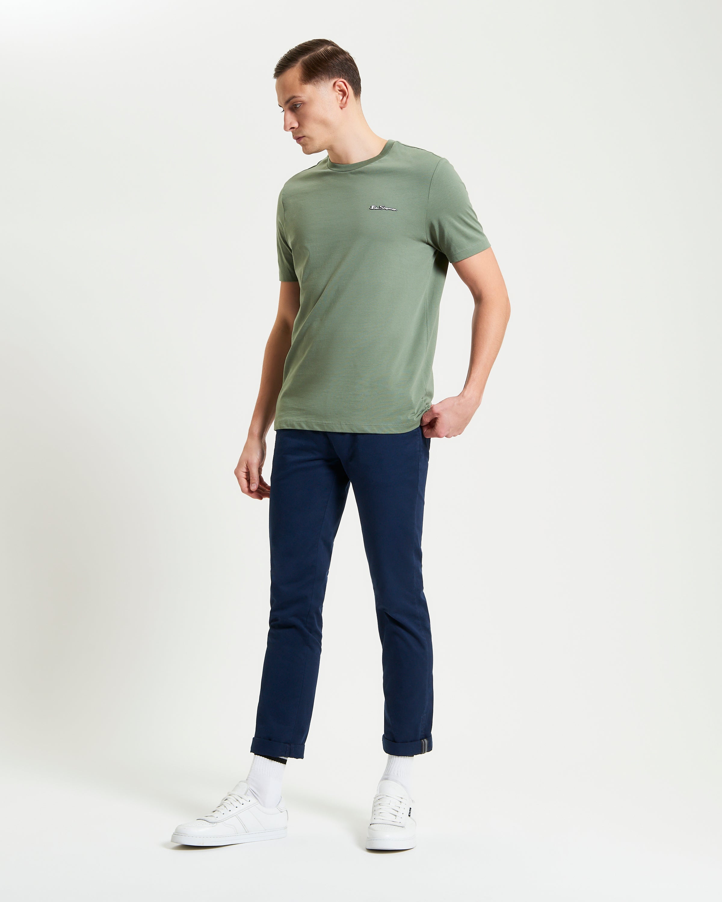 Signature Tee – olive green crew neck t-shirt worn with navy pants, featuring a branded silicon badge for casual style.