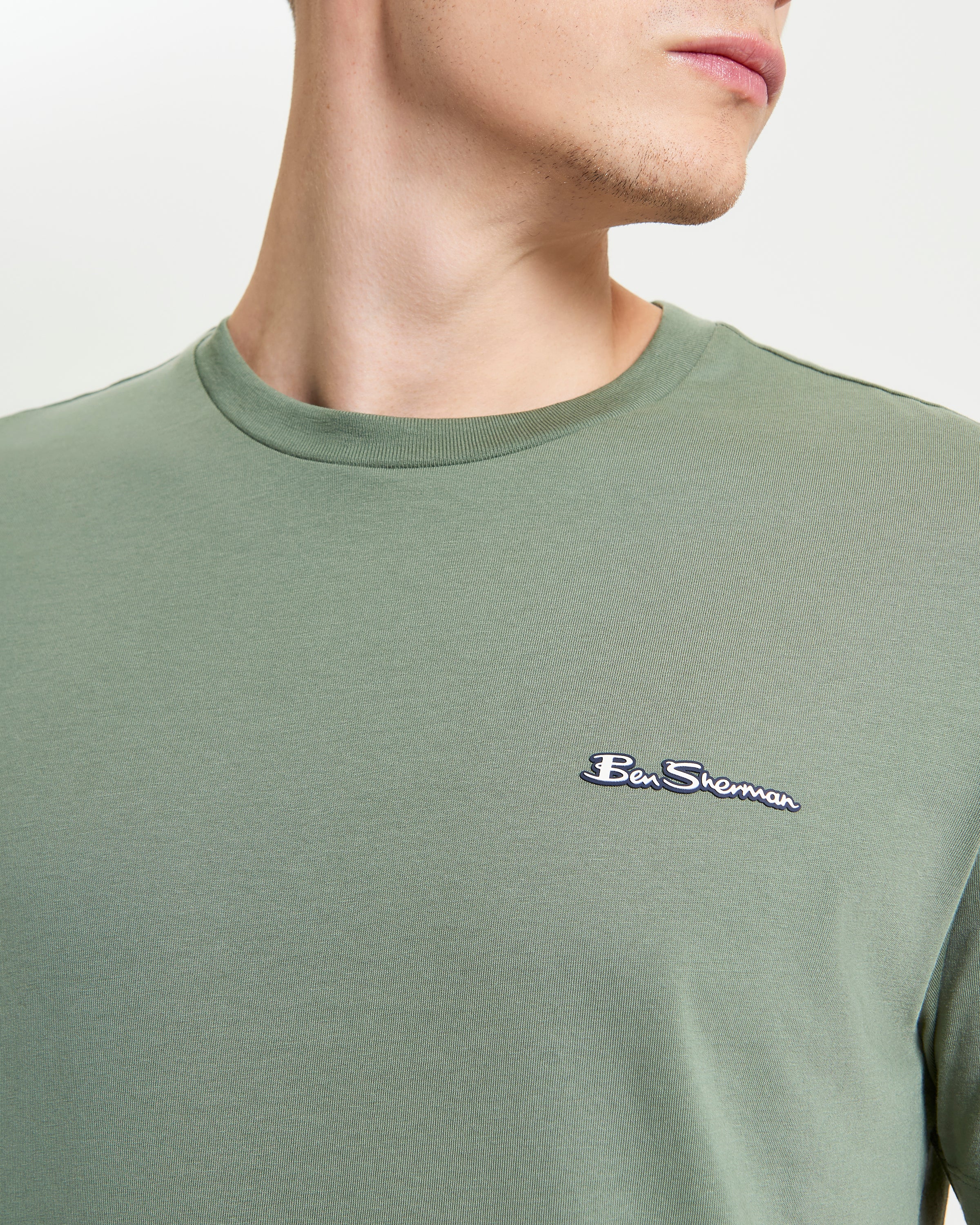 Signature Tee – Branded silicon badge on breathable organic cotton in green color.