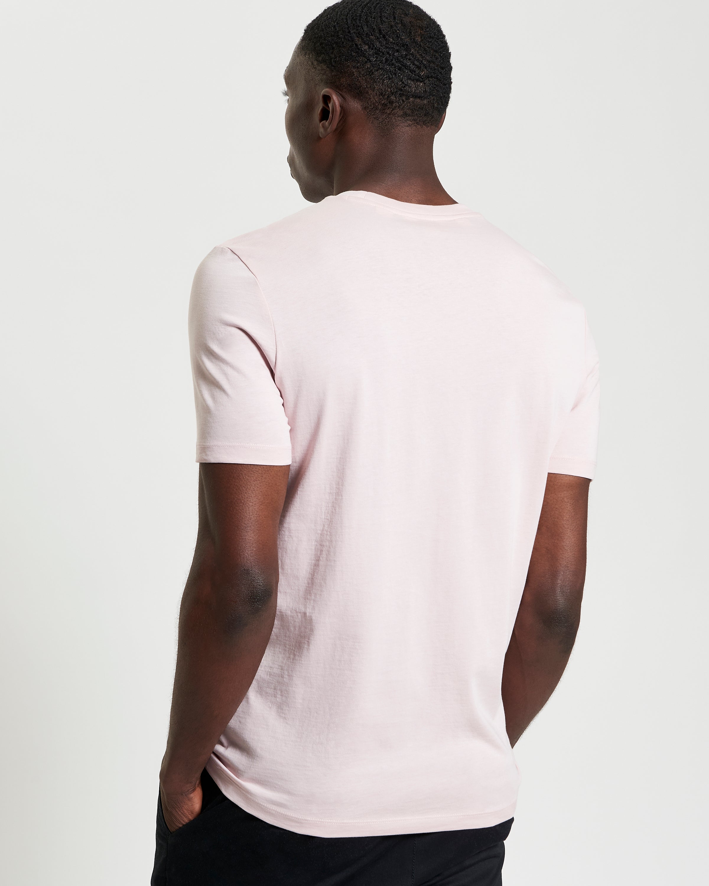 Signature Tee – Side view of a man wearing a light pink crew neck t-shirt.