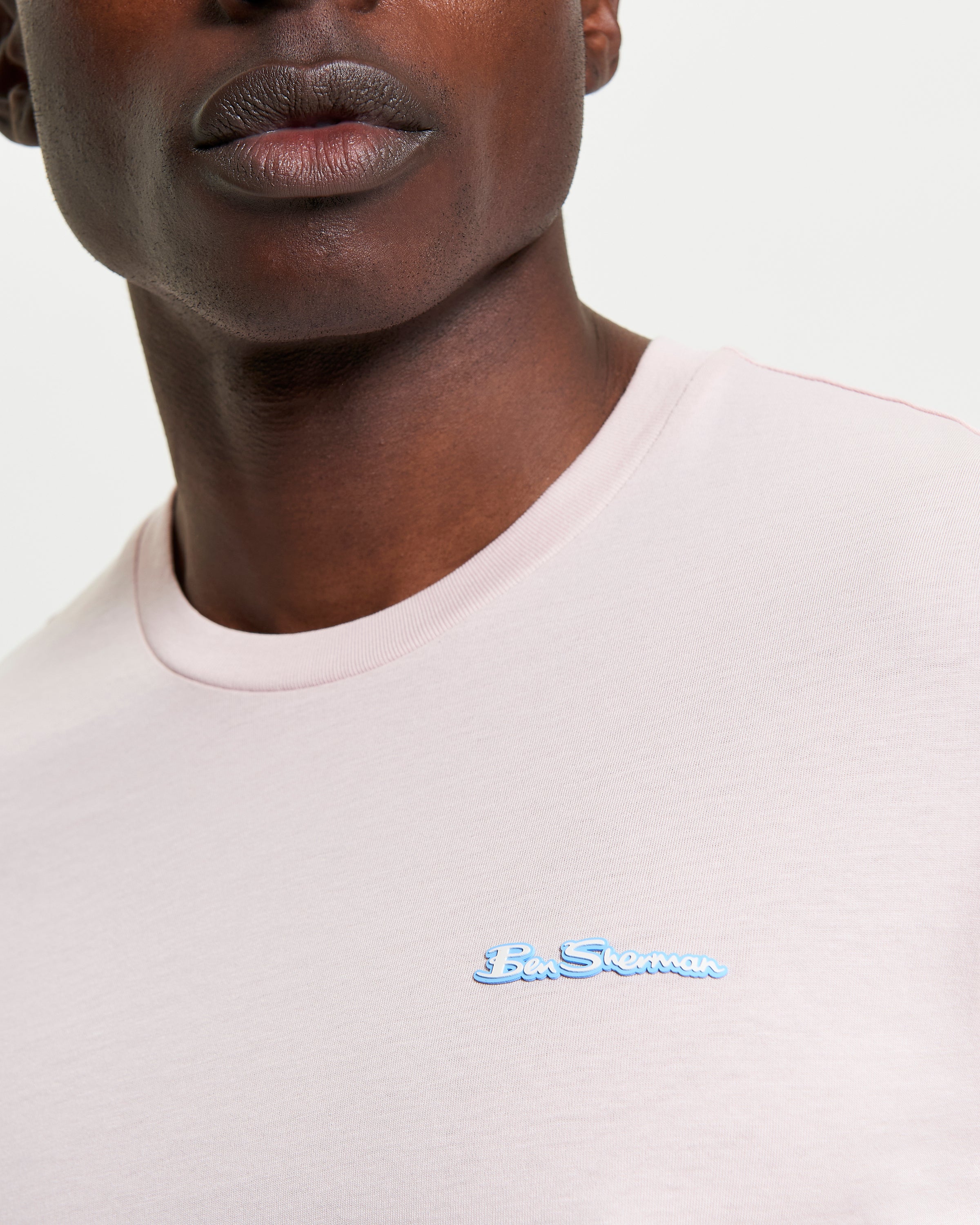 Close-up of a model wearing the Signature Tee with a branded silicon badge in light pink.