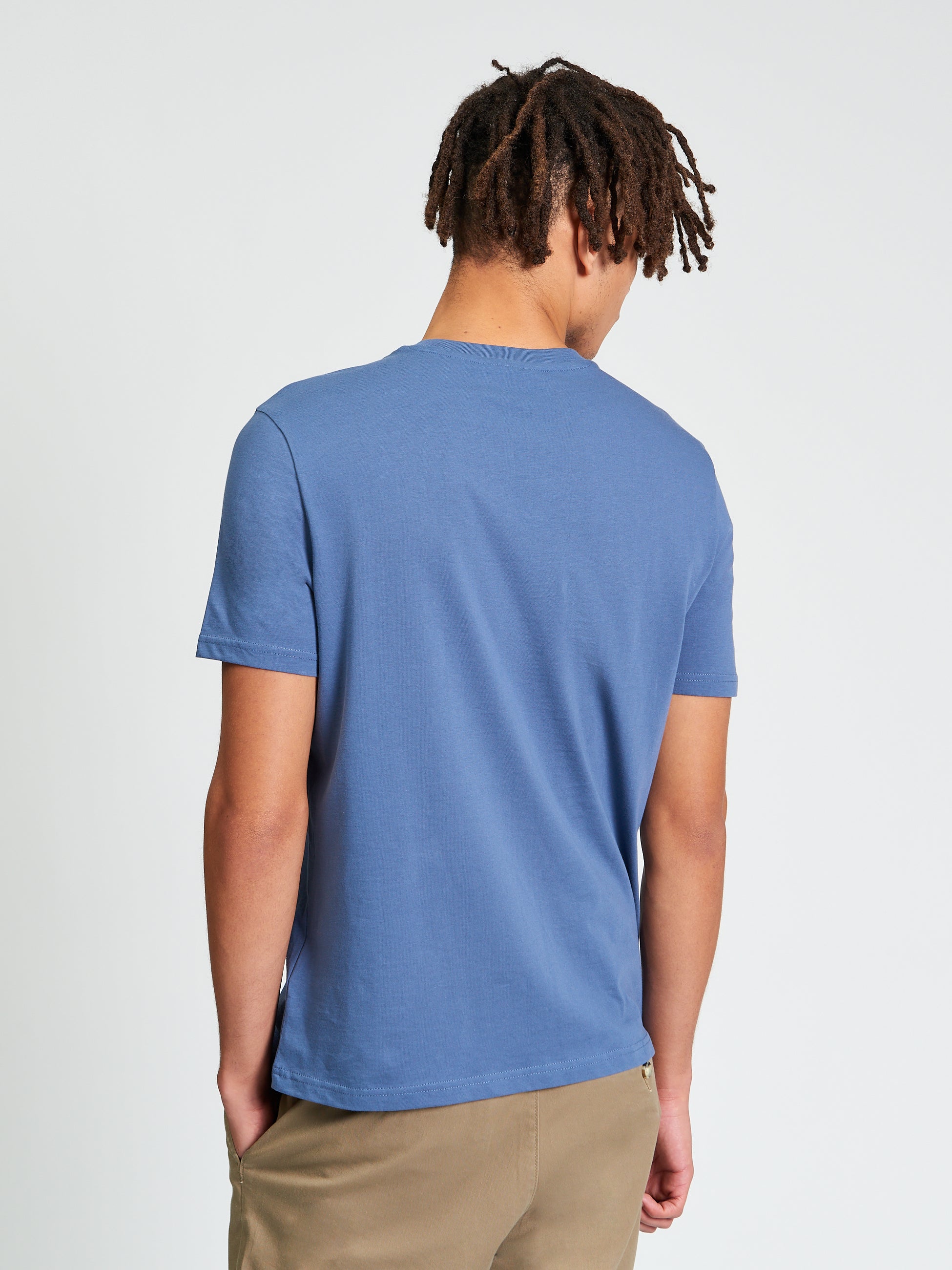 Core Stripe Tee – View of the back of a man wearing a blue t-shirt made from 100% organic cotton.