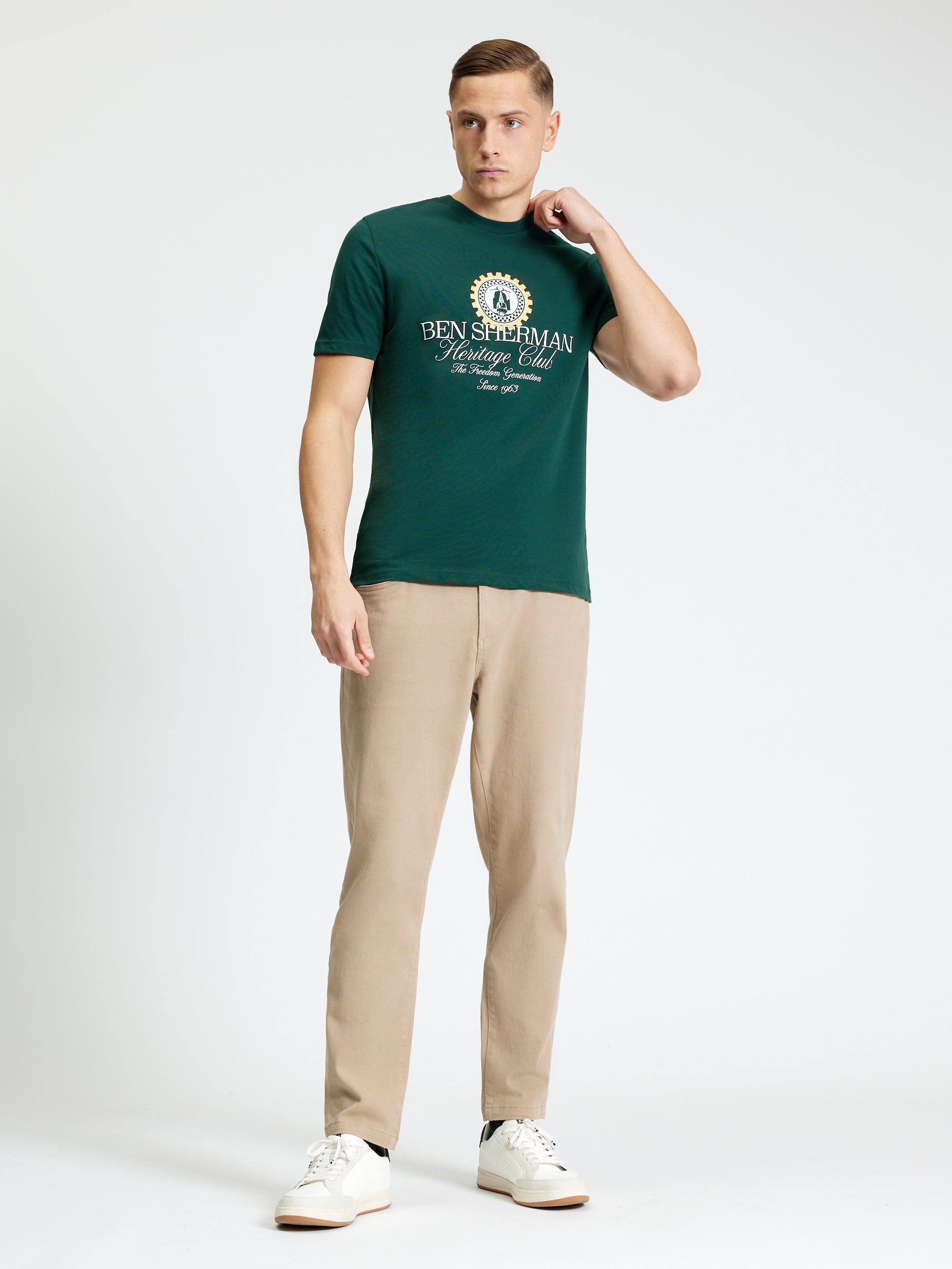 Heritage Club Tee – Ben Sherman model wearing green tee with graphic design and beige pants.