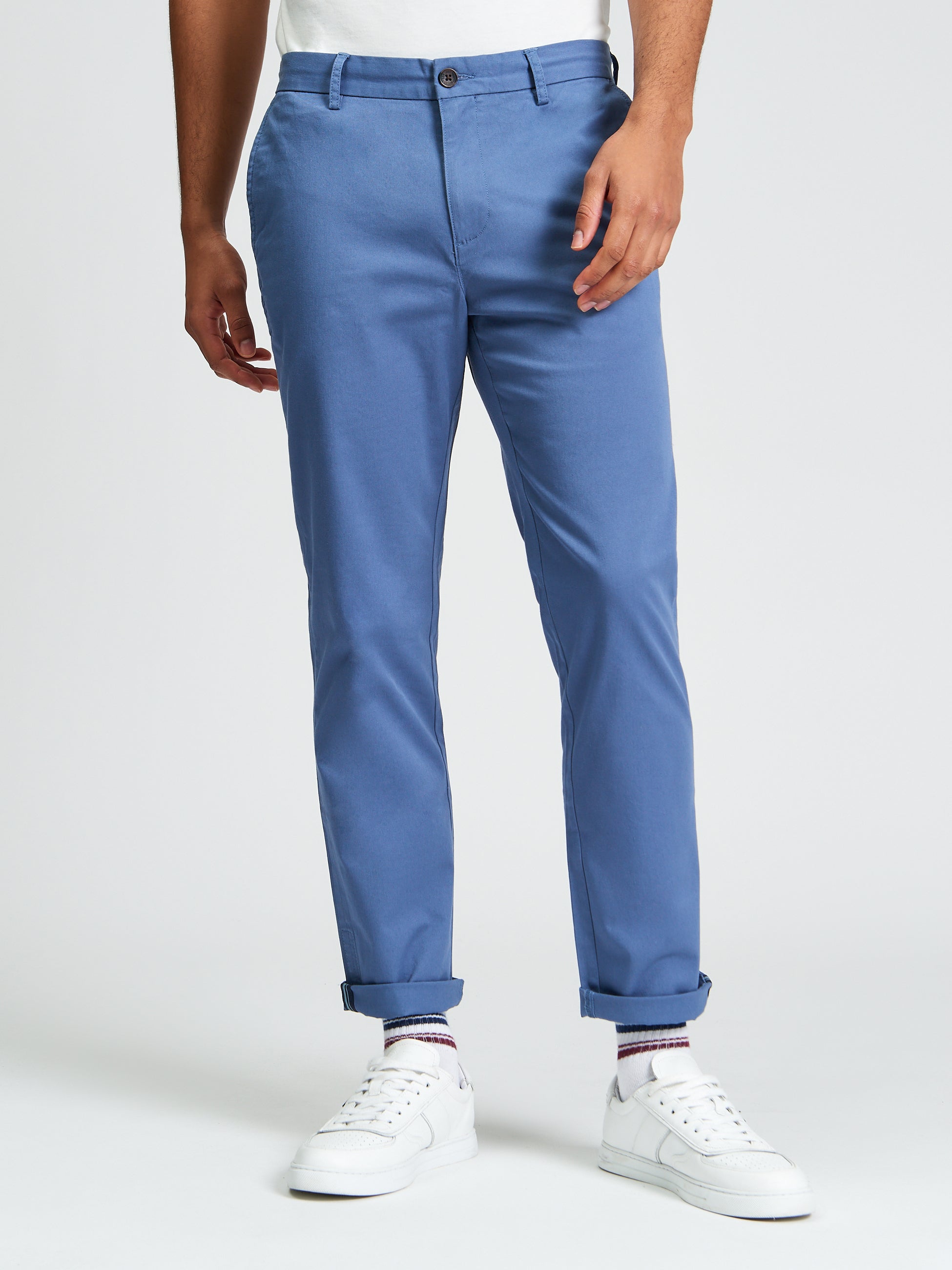 Signature Slim Stretch Chino – blue pants worn with white sneakers and rolled cuffs.