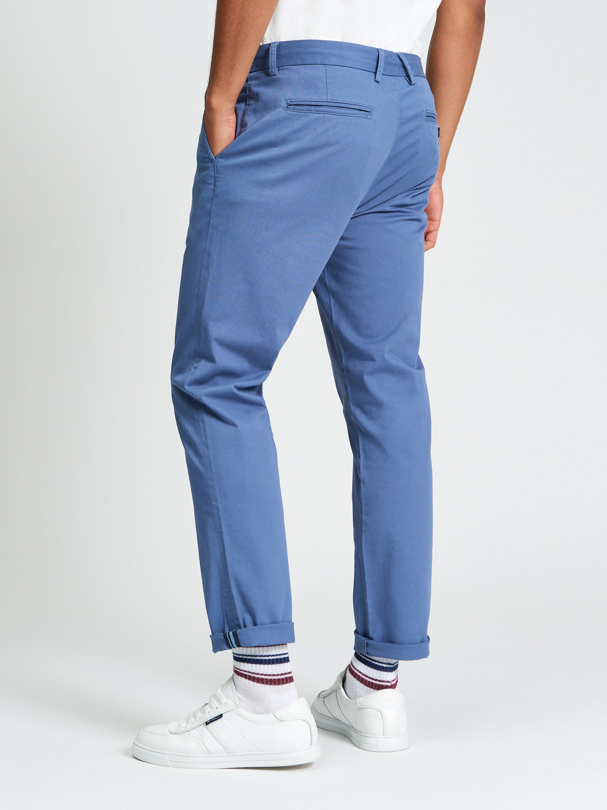 Signature Slim Stretch Chino – blue pants showing back view with rolled cuffs and casual white sneakers.