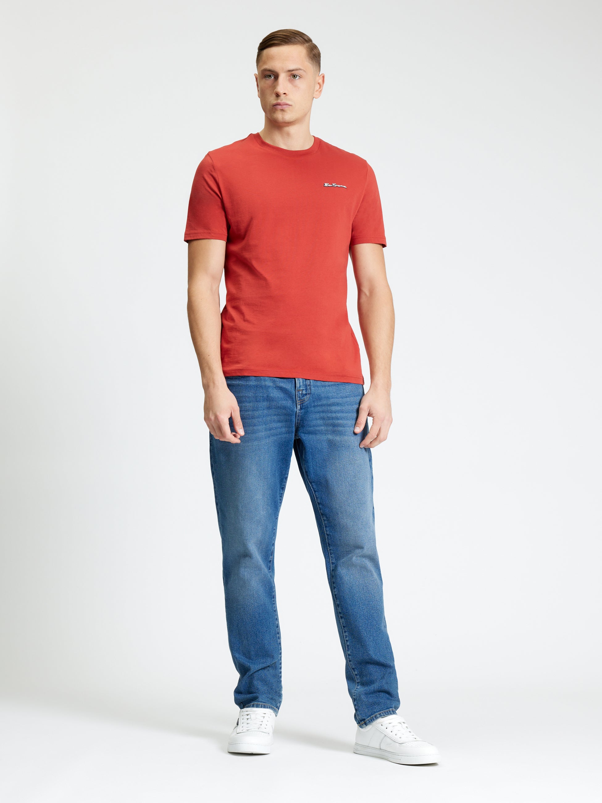Signature Tee – red crew neck t-shirt worn by a man with blue jeans and white sneakers.